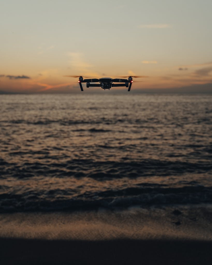 A drone hovers over a tranquil ocean during a stunning sunset, capturing the serene seascape.