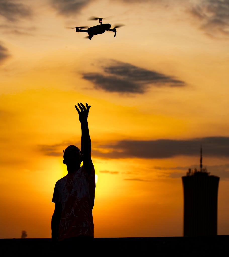 A man with a drone silhouetted against a vibrant Beirut sunset, capturing urban skyline.