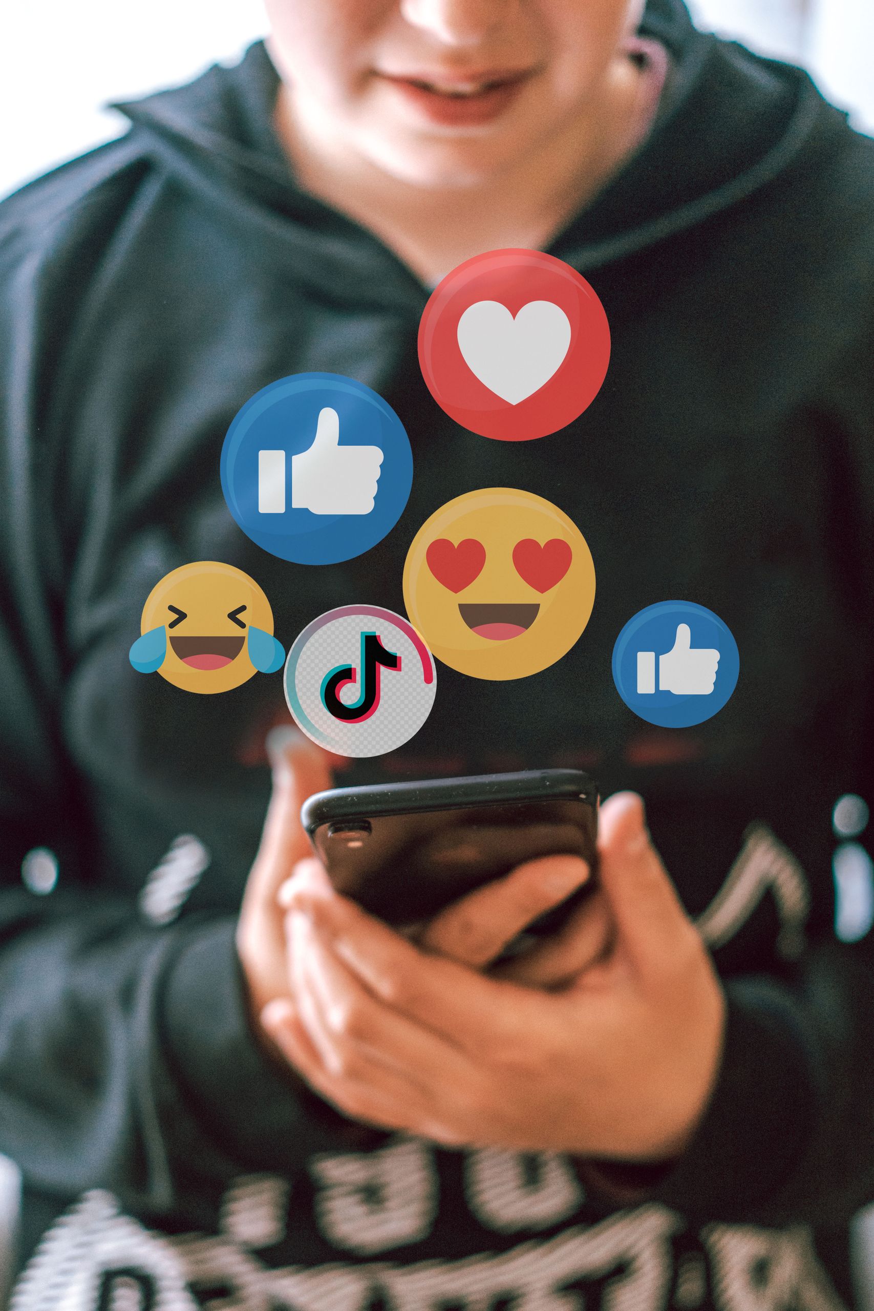 A teenager interacts with social media icons floating over a smartphone, illustrating digital connectivity and engagement.