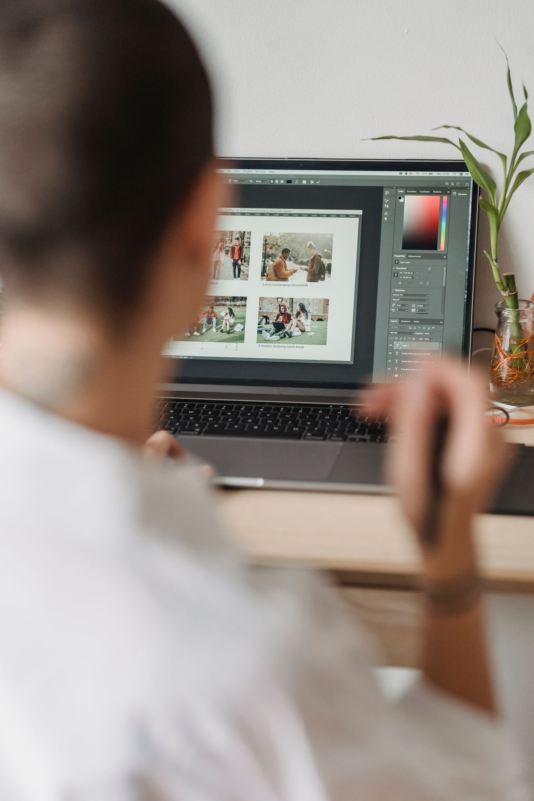 Back view of crop anonymous graphic designer with short hair in white shirt working on laptop using touchpad while retouching photos