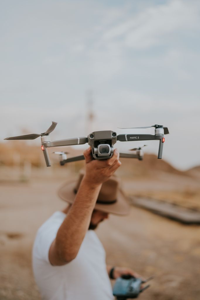Man with a hat holding a DJI drone outdoors in a casual setting, ready for flight.